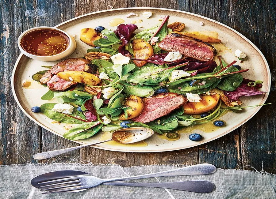 Salade de pêches grillées, magret et myrtilles, noix de pécan et fromage frais