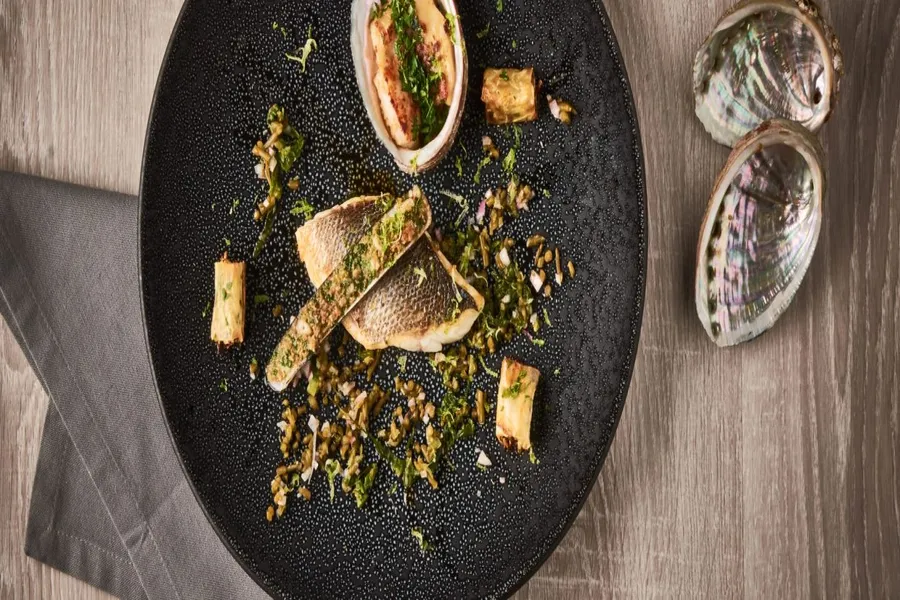 Bar de ligne rôti, couteaux gratinés et ormeaux juste poêlés, cannellonis végétaux à l'huile de sésame, algues en condiments