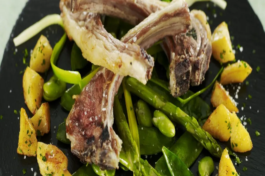Le carré d'agneau d'alsace de lait cuit à la plancha à la fleur de sel, fricassée de pois gourmands, fèves et asperges