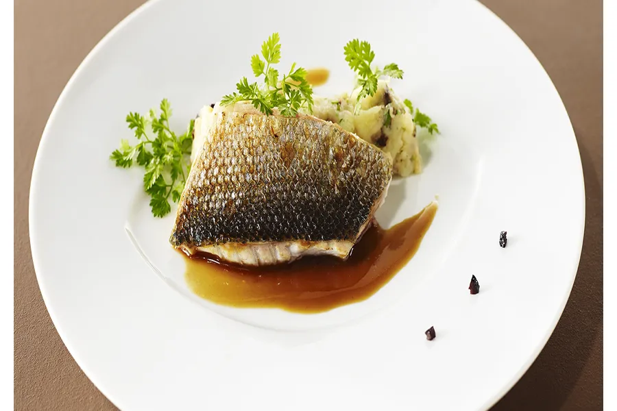 Dos de bar grillé, écrasé de pommes de terre aux olives noires et cébettes, jus d'arêtes