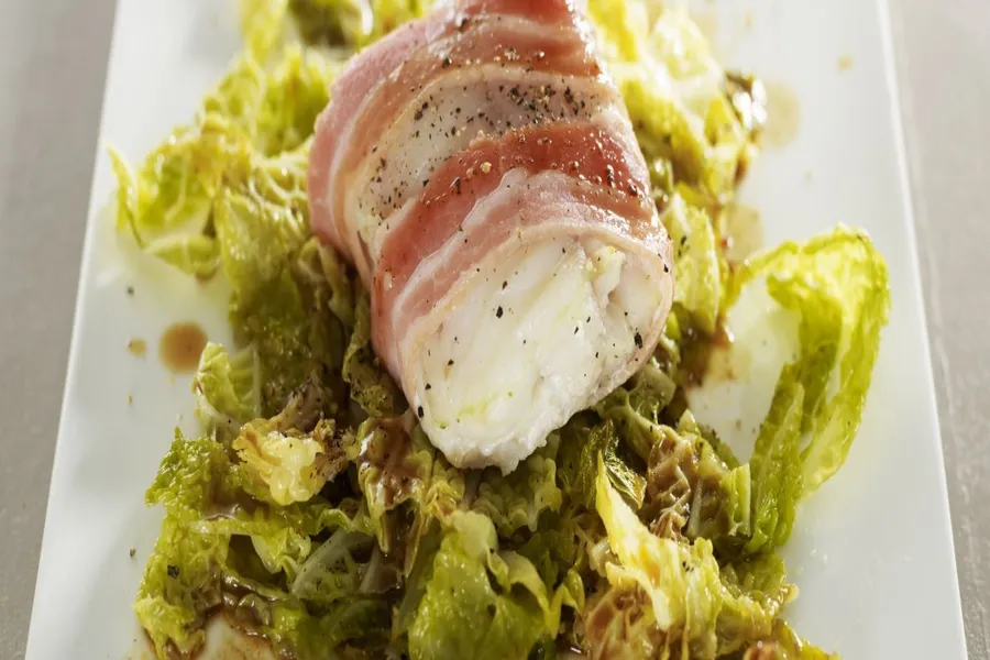 Filet de bar au lard d'arnad, embeurrée de chou vert, jus de poulet