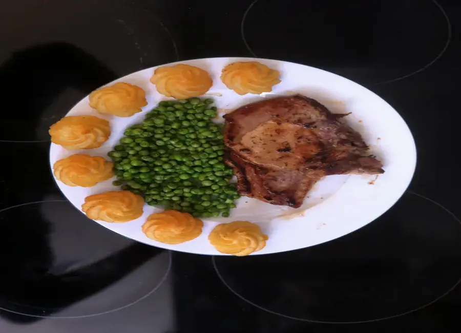 Côtes de porc, pommes duchesses et petits pois étuvés