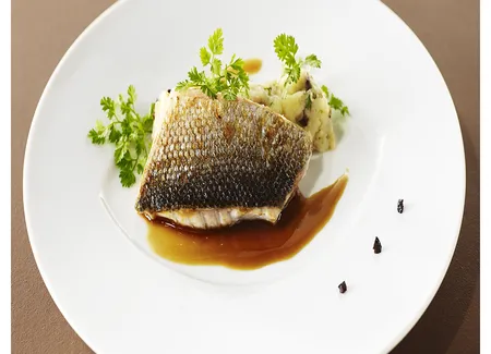 Dos de bar grillé, écrasé de pommes de terre aux olives noires et cébettes, jus d'arêtes