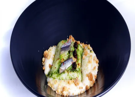 Merlu de ligne cuit à l'huile de persil, confiture d'olive noir, anchois et piments d'espelette, mousse de haricots blancs, crumble à l'ail