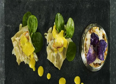 Ravioles de moules et chair de crabe aux jeunes pousses de tétragones, pressée safranée et crème aérienne de pommes de terre violette croustillante
