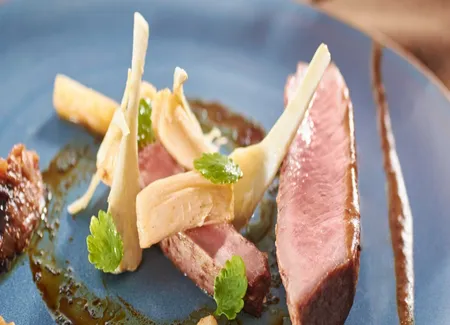 Selle d'agneau de lait, artichauts épineux, salsifis rôtis, fruits secs et sauce au sésame noir