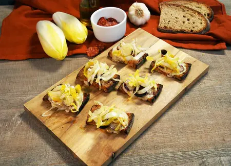 Tartines frottées à l’ail, fromage de brebis, endives et chips de chorizo