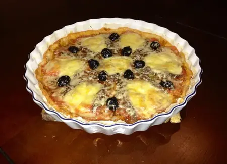 Tarte à la tomate mozzarella aux anchois et aux olives noires sur fondue d'oignon